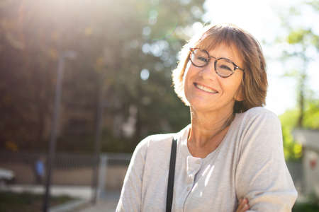 Close up portrait older woman with eyeglasses smiling outsideの写真素材