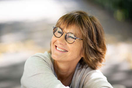 Close up portrait happy woman smiling with eyeglasses and looking awayの写真素材