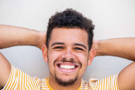 Close up portrait smiling young man with bag and cellphone in city