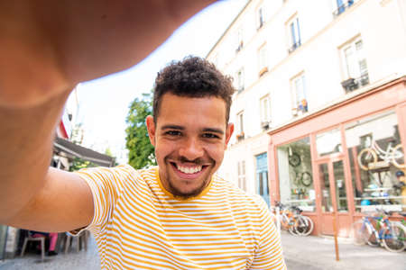 Close up portrait smiling young man with bag and cellphone in city