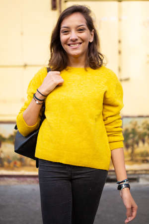 Close up portrait smiling female student with bag and book in cityの写真素材