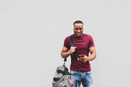 Side portrait smiling African american man sitting outside in city using mobile phone