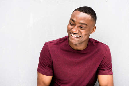 Side portrait smiling African american man sitting outside in city using cellphoneの写真素材