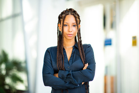 Full length portrait of beautiful young African american woman walking with mobile phone outside in...