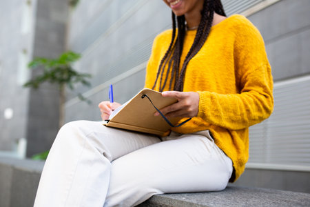 Cropped portrait of woman studying with pen and book while sitting outsideの写真素材