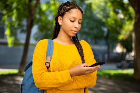 Close-up portrait of young african american woman with bag standing outside and looking at her...