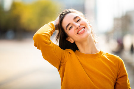 Portrait of beautiful young woman talking on mobile phone while writing book outsideの写真素材