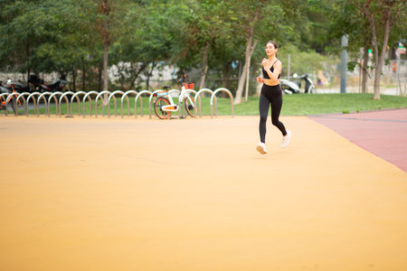 Full length portrait of healthy young woman in sportswear on morning run in the park