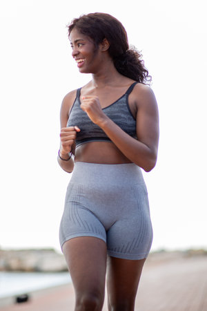 woman running along a waterfront, showcasing a vibrant expression and active lifestyle