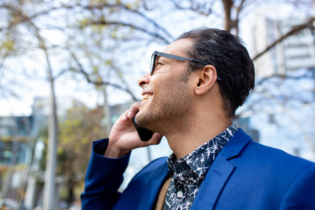Close up profile shot of happy young african american businessman talking on cell phone outside in the cityの写真素材