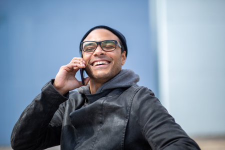 Portrait of happy young african man enjoying talking on mobile phone outsideの写真素材