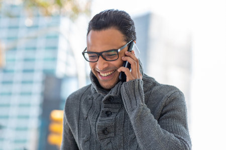 Close up portrait of smiling young african man with eyeglasses talking on cell phone outsideの写真素材