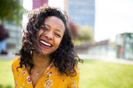 Close up portrait of cheerful young african woman laughing outsideの写真素材