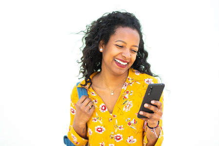 Portrait of cheerful young african american woman looking at cellphone against white background
