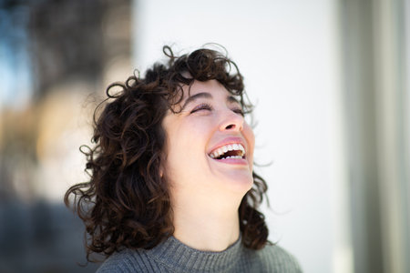 Close-up portrait of beautiful young woman with short hair laughing outsideの写真素材