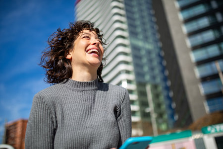 Close-up portrait of young woman with cellphone walking outside in the cityの写真素材