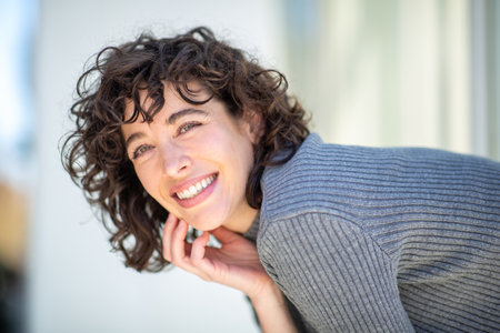 Close-up portrait of young woman looking at camera and smiling outsideの写真素材