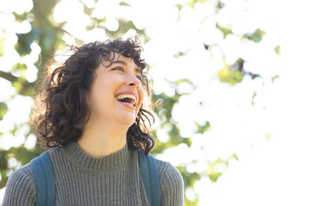 Close-up portrait of attractive young woman looking away and smiling outside on a sunny dayの写真素材