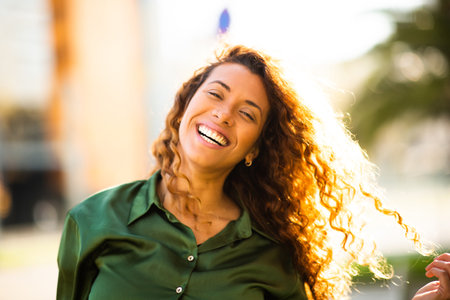 Close up portrait of beautiful young latin woman with brown hair looking at camera and smiling outside on a summer dayの写真素材