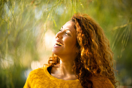 Close up portrait of pretty young woman looking away and smiling outdoors on a summer dayの写真素材