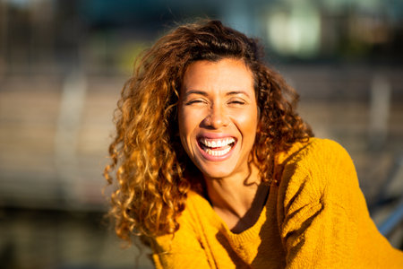 Close up portrait of laughing young hispanic woman looking at camera outsideの写真素材