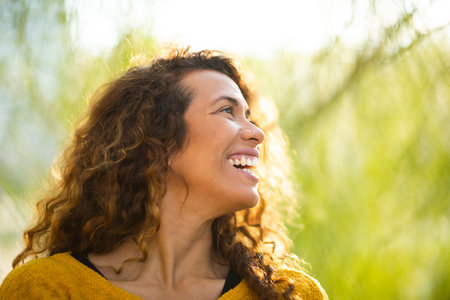 Close up portrait of pretty young woman looking away and smiling outsideの写真素材