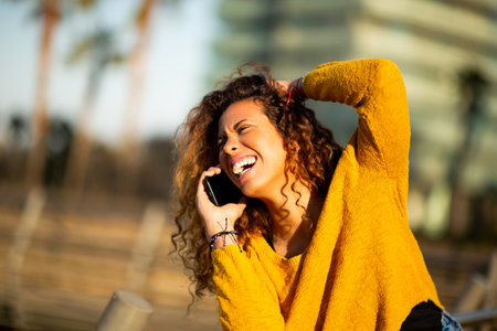 Portrait of cheerful young latin woman making a phone call outside in the cityの写真素材