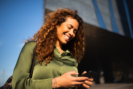 Portrait of attractive latin woman walking outside with cell phoneの写真素材