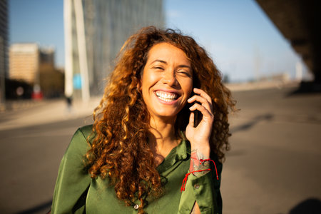 Close up portrait of smiling young woman talking on mobile phone outdoors in the cityの写真素材