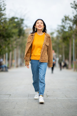 Full body portrait smiling young asian woman walkingの写真素材
