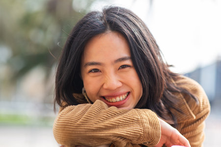 Close up portrait smiling young asian woman sitting on benchの写真素材