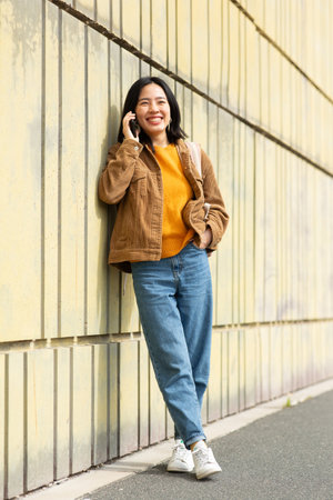 Full body portrait smiling young asian woman talking with phoneの写真素材