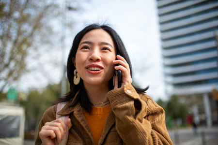 Close up portrait young chinese woman talking with mobile phone in cityの写真素材