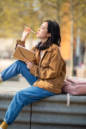 Portrait young thinking woman sitting outside with bookの写真素材