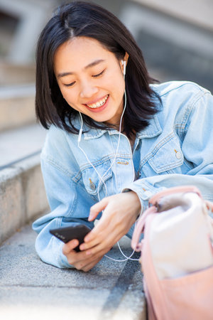 Portrait young woman listening to music with mobile phone and earphonesの写真素材