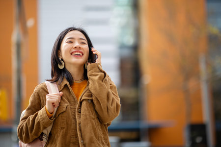 Portrait young asian woman with bag and talking mobile phoneの写真素材