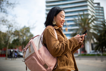 Side portrait student with bag looking at mobile phoneの写真素材