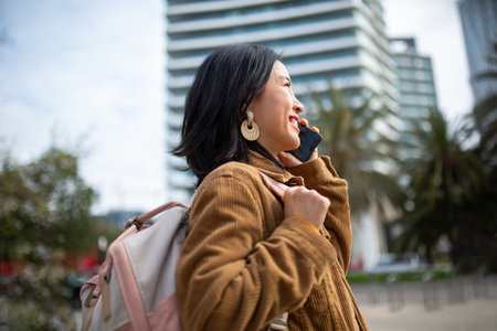 Side portrait young woman walking with bag and mobile phoneの写真素材