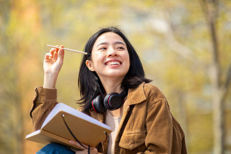 Portrait smiling young asian student with book and pen