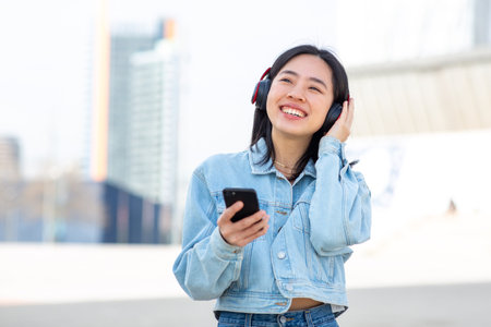 Portrait happy young woman listening to music with mobile phone and headphonesの写真素材