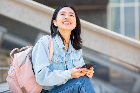 Portrait smiling young woman sitting with phoneの写真素材