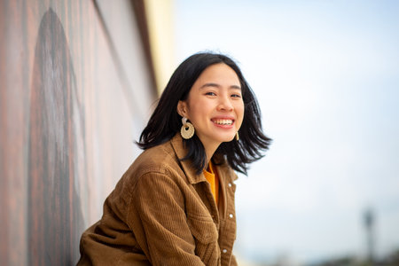 Portrait young woman smiling by wall outsideの写真素材