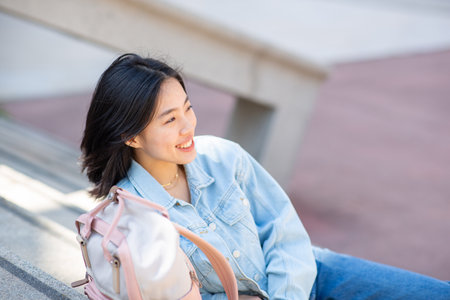 Portrait smiling young woman sitting outside with bagの写真素材