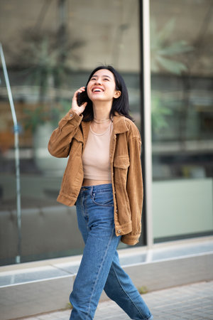 Portrait young woman walking in city talking with mobile phoneの写真素材
