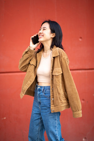 Portrait happy young woman walking and talking with mobile phoneの写真素材