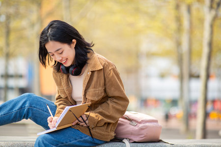 Portrait young woman sitting outside writing in bookの写真素材