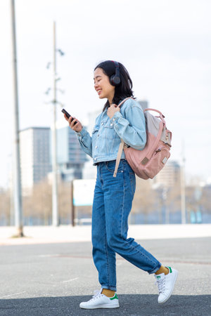 Full body portrait young woman walking with bag and cellphoneの写真素材