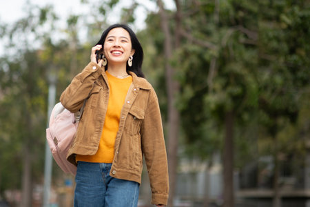 portrait smiling young asian woman walking with mobile phone and bagの写真素材