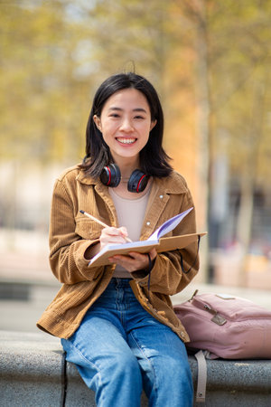 Portrait young woman sitting with book and penの写真素材