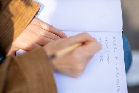 Close up female hand using pen to write in book